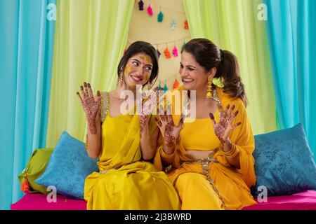 Mutter und Tochter zeigen auf der Haldi-Zeremonie ihre Handflächen mit Mehndi malen Stockfoto