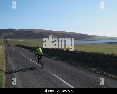 Frau, die auf ruhigen Orkney-Straßen unterwegs ist Stockfoto