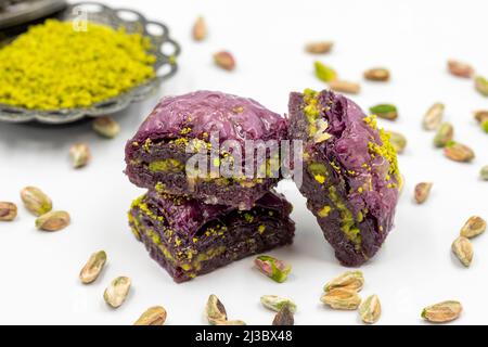 Pistazien lila Baklava auf weißem Hintergrund. Baklava speziell für Diabetiker vorbereitet. Traditionelle Köstlichkeiten der mediterranen Küche. Nahaufnahme Stockfoto