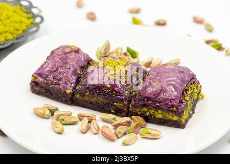 Pistazien lila Baklava auf weißem Hintergrund. Baklava speziell für Diabetiker vorbereitet. Traditionelle Köstlichkeiten der mediterranen Küche. Nahaufnahme Stockfoto