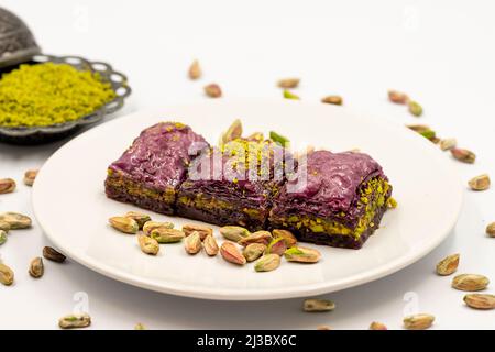 Pistazien lila Baklava auf weißem Hintergrund. Baklava speziell für Diabetiker vorbereitet. Traditionelle Köstlichkeiten der mediterranen Küche. Nahaufnahme Stockfoto