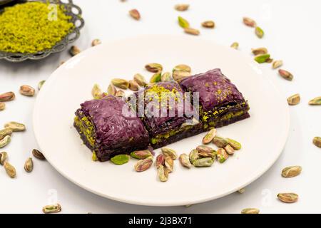 Pistazien lila Baklava auf weißem Hintergrund. Baklava speziell für Diabetiker vorbereitet. Traditionelle Köstlichkeiten der mediterranen Küche. Nahaufnahme Stockfoto