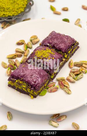 Pistazien lila Baklava auf weißem Hintergrund. Baklava speziell für Diabetiker vorbereitet. Traditionelle Köstlichkeiten der mediterranen Küche. Nahaufnahme Stockfoto