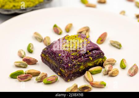 Pistazien lila Baklava auf weißem Hintergrund. Baklava speziell für Diabetiker vorbereitet. Traditionelle Köstlichkeiten der mediterranen Küche. Nahaufnahme Stockfoto