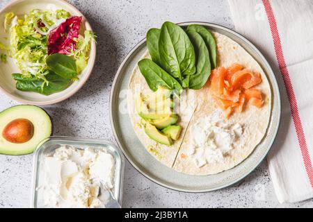 Kochvorgang für Sandwich und Zutaten. Prozess der Zubereitung von Quesadilla mit Avocado, Lachs, Quark und Spinat. Trendy Wrap Hack. Schritt für Schritt Stockfoto