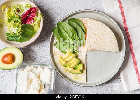 Kochvorgang für Sandwich und Zutaten. Prozess der Zubereitung von Quesadilla mit Avocado, Lachs, Quark und Spinat. Trendy Wrap Hack. Schritt für Schritt Stockfoto