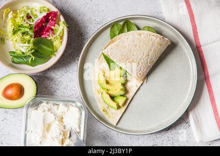 Kochvorgang für Sandwich und Zutaten. Prozess der Zubereitung von Quesadilla mit Avocado, Lachs, Quark und Spinat. Trendy Wrap Hack. Schritt für Schritt Stockfoto