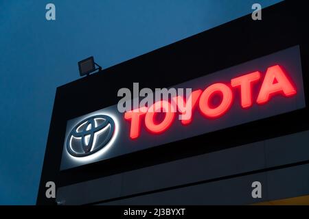 Batumi, Georgia - Januar 26 2022: Nahaufnahme des Toyota Händlerlogos, das abends auf dem Gebäude gegen den Himmel beleuchtet wird Stockfoto