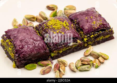 Pistazien lila Baklava auf weißem Hintergrund. Baklava speziell für Diabetiker vorbereitet. Traditionelle Köstlichkeiten der mediterranen Küche. Close up bakla Stockfoto