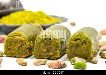 Baklava eingewickelt in Pistazie auf weißem Hintergrund. Traditionelle mediterrane Köstlichkeiten. Nahaufnahme Pistazien Baklava. Lokaler Name fistik sarma Stockfoto