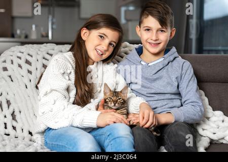 Bengalkatze im Wohnzimmer auf der Couch mit Kindern Stockfoto