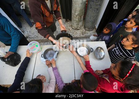 Palästinensische Kinder halten ihre Töpfe aus, um Suppe in einem Zentrum einer lokalen Wohltätigkeitsgruppe zu bekommen, die während des heiligen Monats Ramadan im Al-Nuseirat Flüchtlingslager im zentralen Gazastreifen kostenloses Essen anbietet. Muslime auf der ganzen Welt, vor allem im heiligen Monat Ramadan, bieten eine Menge von Wohltätigkeitsorganisationen wie kostenlose Mahlzeiten Verteilungszentren an, die sie als „Tekeya“ für arme Menschen bezeichnen. (Foto von Ahmed Zakot / SOPA Images/Sipa USA) Stockfoto