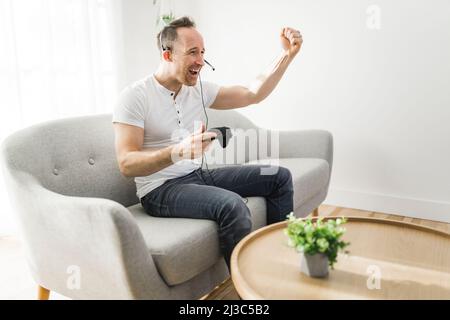 Konzentrierter Mann, der sich auf einem Sofa mit Videospielen amüsieren kann Stockfoto