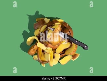 Konzept der Stop Food Waste Day. Kartoffelschalen sind eines der am häufigsten entsorgten Produkte während der Lebensmittelzubereitung. Grüner Hintergrund. Stockfoto