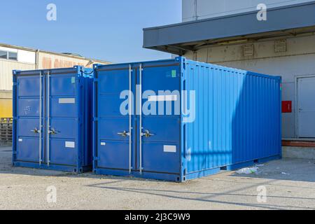 Zwei Blue Shipping Cargo Container vor dem Lagerhaus, provisorische Lagerlösung Stockfoto