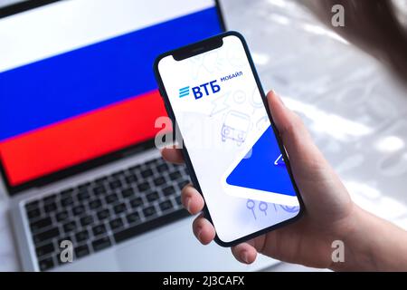 SPB, Russland - 7. April 2022: VTB Mobile Banking App in Russland. Hand mit Smartphone, Logo auf dem Bildschirm. Hintergrund mit Nationalflaggenfoto Stockfoto