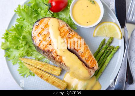 Gegrillter Lachs mit Spargel, Mais-Mini und Sauce Hollandaise. Nahaufnahme. Stockfoto