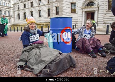 London, England, Großbritannien. 7. April 2022. Demonstranten hielten sich an einem Fass fest. Extinction Rebellion Ärzte und Gesundheitspersonal blockierten am Weltgesundheitstag die Straße vor dem Finanzministerium von HM in Westminster, aus Protest gegen die Finanzierung fossiler Brennstoffe durch die Regierung. Mehrere Demonstranten klebten sich an Fässer. (Bild: © Vuk Valcic/ZUMA Press Wire) Stockfoto