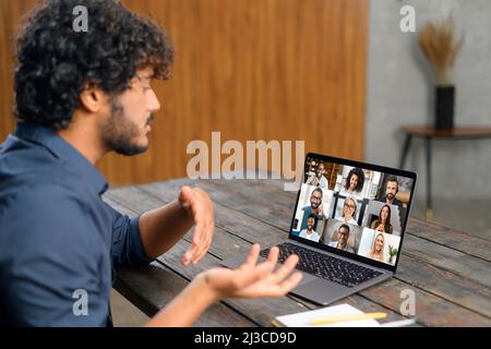 Blick von hinten über der Schulter auf dem Laptop mit verschiedenen Mitarbeitern, Kollegen auf dem Bildschirm, Videoanruf, Online-Meeting. App für Videokonferenzen mit vielen Menschen zusammen Stockfoto