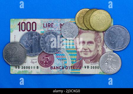 Foto eines italienischen Banknotens vor dem Euro 1000 Lire und Münzen mit französischen 2-Franken-1/2-Franken- und 20-Centime-Münzen Stockfoto