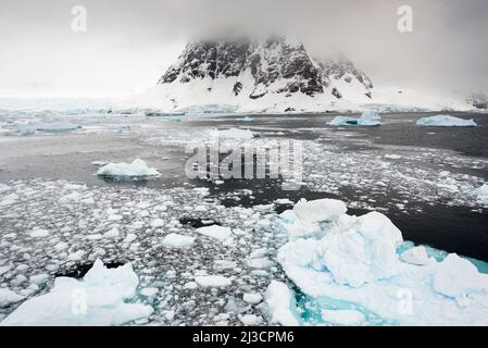 Wolken bedecken Hügel am nördlichen Ende des Lemaire-Kanals, von denen viele mit Meereis bedeckt sind. Antarktis Stockfoto