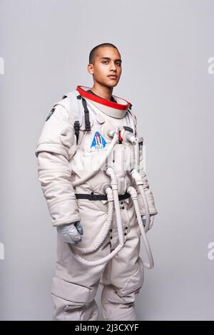 Kolumbianischer männlicher Astronaut in Uniform, bereit für die Untersuchung des Kosmos, der im Studio steht und auf die Kamera schaut Stockfoto