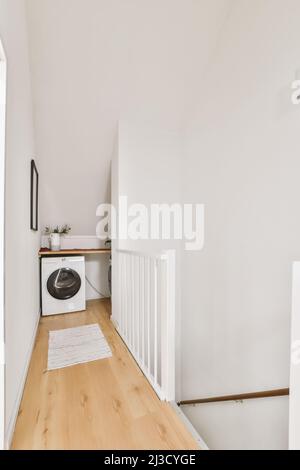 Innenraum der engen Waschküche mit Waschmaschine im Dachgeschoss mit weißen Wänden in der Hütte platziert Stockfoto