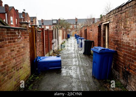 Die Hinterstraße aus Reihen von Reihenhäusern in einer heruntergekommenen Stadt in Nordengland mit Mülltonnen, die für die Sammlung am Straßenrand mit Kopierplatz ausgelassen wurden Stockfoto