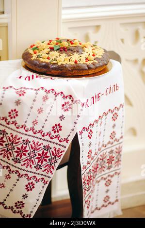 Traditionelles rundes Brot mit Dekoration auf besticktem Handtuch. Ukrainische Hochzeitszeremonie. Stockfoto