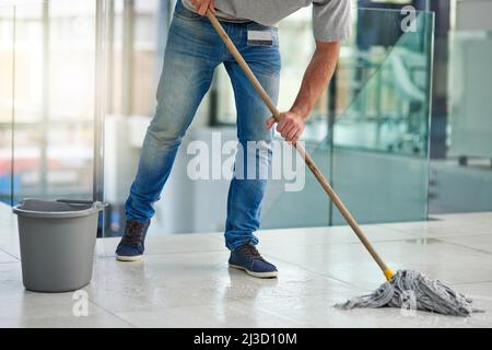 Es ist ein gut gepflegtes Büro. Aufnahme eines nicht erkennbaren Mannes, der die Büroetage wischt. Stockfoto