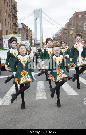 Mitglieder einer irischen Tanzschule treten bei der Saint Patrick's Day Parade entlang der 3. Avenue in Bay Ridge Brooklyn auf. Von der Verrazano-Brücke aus sieht man im Hintergrund einen Turm. Stockfoto