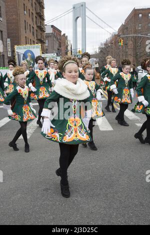 Mitglieder einer irischen Tanzschule treten bei der Saint Patrick's Day Parade entlang der 3. Avenue in Bay Ridge Brooklyn auf. Von der Verrazano-Brücke aus sieht man im Hintergrund einen Turm. Stockfoto