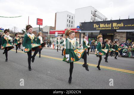 Mitglieder einer irischen Tanzschule treten bei der Saint Patrick's Day Parade entlang der 3. Avenue in Bay Ridge Brooklyn auf. Von der Verrazano-Brücke aus sieht man im Hintergrund einen Turm. Stockfoto