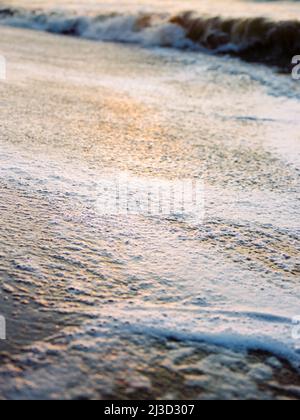 Malerische Seeslandschaft mit ruhigen Wellen bei Sonnenuntergang und Meeresschaum Stockfoto