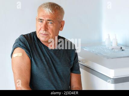 Alte Männer nach COVID-19-Impfstoff. Älterer Mann. Impfstoff aus Coronavirus. Impfung für ältere Menschen. Älterer Mann zeigt ihren Arm mit Verband, Patch Stockfoto