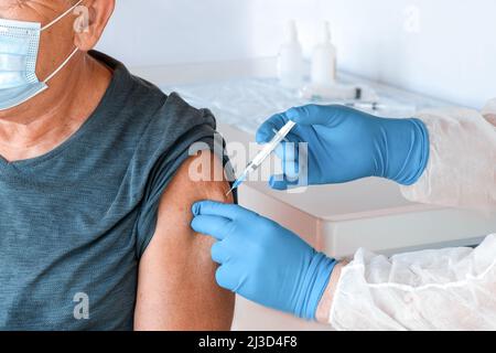 Arzt, Der Den Älteren Mann In Der Klinik Impft. Impfung Älterer Menschen. Arzt verabreichen COVID19 Coronavirus-Impfstoff Injektion an alten Mann in Gesichtsmaske Stockfoto