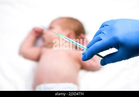 Kinderarzt impft Neugeborenes. Impfstoff, Impfung von Kleinkindern Soft Focus Spritze in die Hände der Krankenschwester und verschwommener Hintergrund des Säuglings Stockfoto
