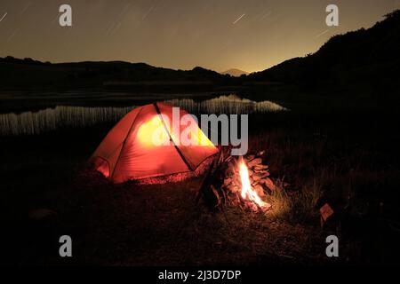 Lagerfeuer in der Nähe eines beleuchteten Zeltes am Biviere See im Nebrodi Park, Sizilien Stockfoto