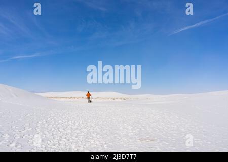 Menschen wandern durch die weißen Gipsdünen im White Sands National Park in New Mexico stehen an einem sonnigen Tag vor einem großen blauen Himmel. Stockfoto