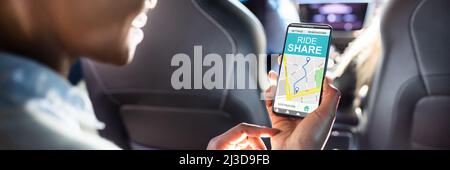 Afrikanische Frau mit Car Sharing App beim Sitzen im Auto. Stockfoto