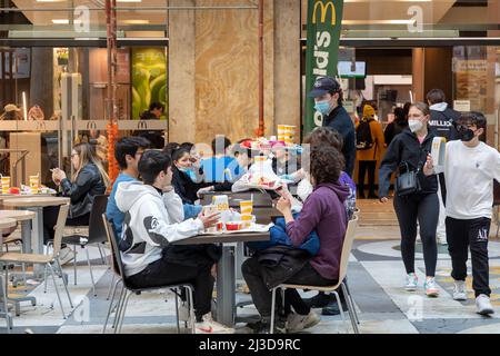 Neapel, Italien - 25. März 2022: Gruppe junger Teenager, die an einem McDonald's-Tisch sitzen und in Papierverpackungen essen. Stockfoto