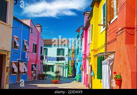 Venedig (Burano), Italien - Mai 9. 2019: Blick auf eine leere Gasse mit bunten bunten Häusern vor klarem blauen Himmel Stockfoto