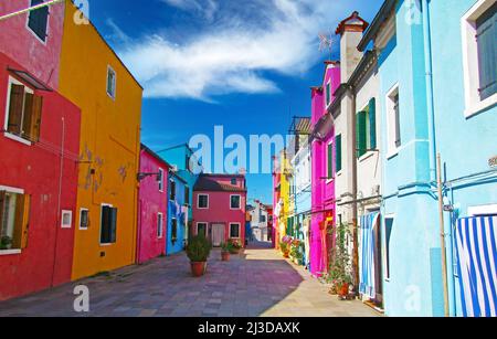 Venedig (Burano), Italien - Mai 9. 2019: Blick auf eine leere Gasse mit bunten bunten Häusern vor klarem blauen Himmel Stockfoto