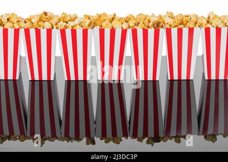 Kino-, Film- und Theaterkonzept. Popcorn-Boxen mit weißen und roten Streifen voller Süße mit Karamell-Popcorn auf schwarzem reflektierendem Hintergrund in Weiß Stockfoto