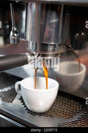 Cremiger Kaffee, der aus der Nähe aus einer Kaffeemaschine gegossen wird Stockfoto