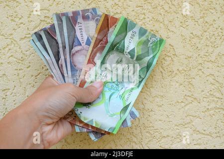 Barbados Moderne Banknoten in weiblicher Hand auf leichter Textur. Stockfoto