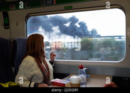 Frau GWR-Zugfahrerin, die am 5. April 2022 in Southall West London aus dem Fenster auf den wabenden Rauch aus dem Feuer schaute. England Großbritannien KATHY DEWITT Stockfoto