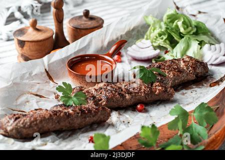 Kebab mit Sauce und Grünzeug auf einem Teller Stockfoto