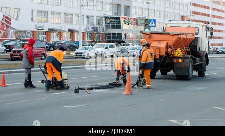 Minsk, Weißrussland - 24. März 2022: Straßenarbeiter reparieren Asphaltbelag auf der Straße Stockfoto