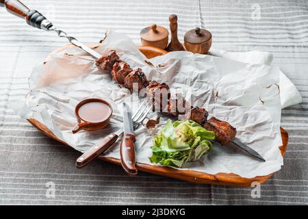 Grillen Sie mit Tomaten und Kräutern auf einem Holzteller mit Papier Stockfoto